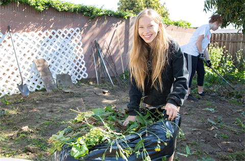 Teen volunteer pushing wheelbarrow 